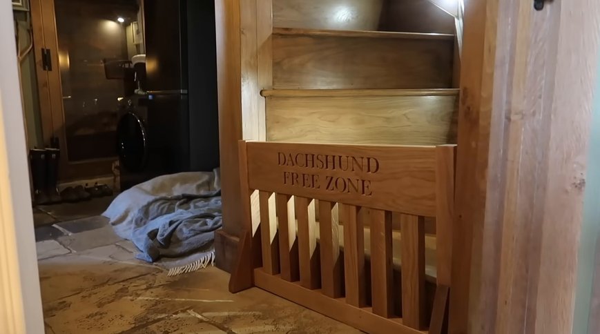 The DACHSHUND FREE ZONE dog gate at the foot of the stairs. Still: Josie Irons on YouTube