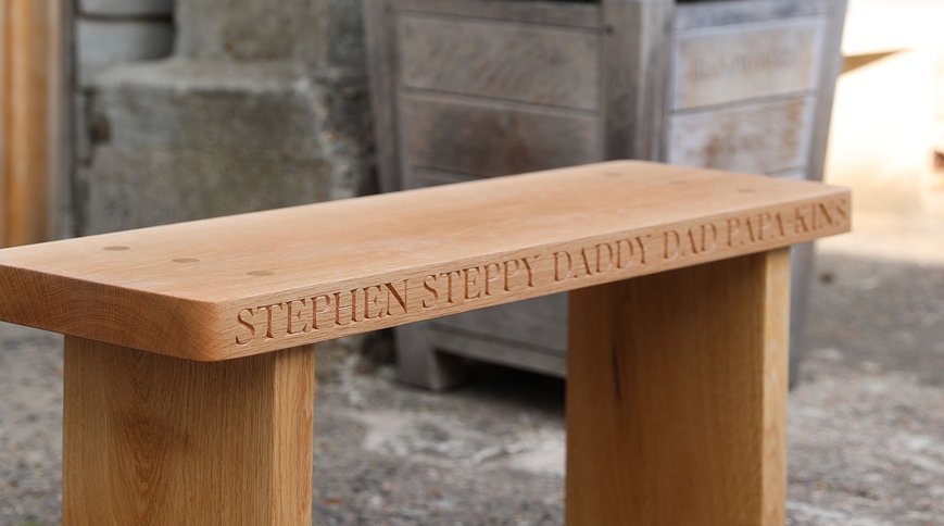 An oak bench carved with family names along the seat