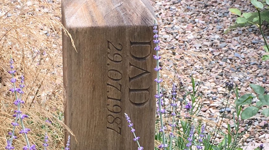 A bespoke oak memorial carved DAD, among lavender