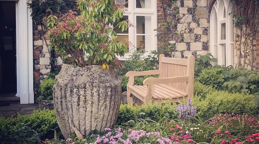 An oak parkland bench in a flint-walled garden