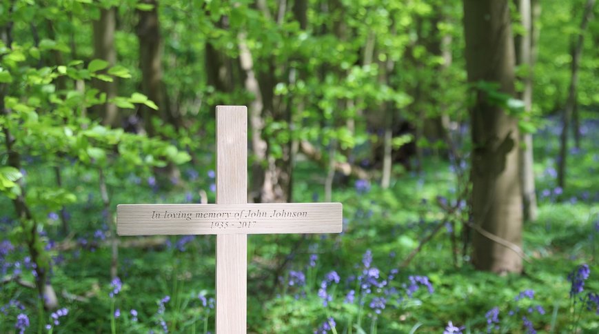 An oak memorial cross in a bluebell wood